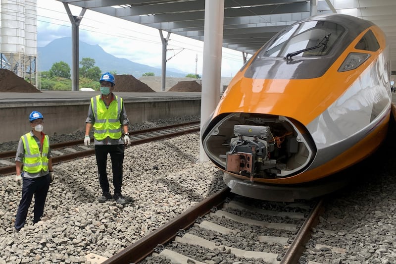 Workers stand beside a high-speed train for a rail link project that is part of China's Belt and Road Initiative, in Bandung, West Java province, Indonesia, in Oct. 2022. (Reuters)