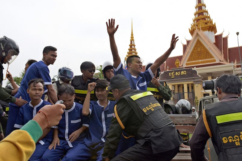 Cambodian security officers detain protesters in prisoner uniforms as they demonstrate against a controversial law regulating non-governmental organizations outside the National Assembly building in Phnom Penh, July 26, 2015. (Tang Chhin Sothy/AFP)