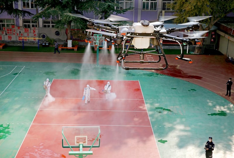 A drone sprays disinfectant over volunteers disinfecting a school following local cases of the coronavirus disease (COVID-19) in Lanzhou, Gansu province, China October 27, 2021. Credit: Reuters