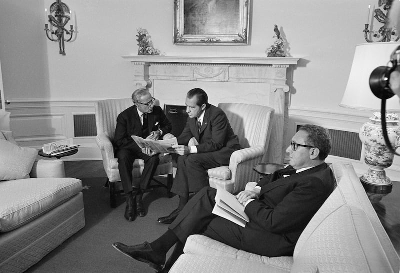 President Richard Nixon and Ambassador Agha Hilaly of Pakistan huddle over a newspaper account as they discuss the devastation in Pakistan, at the White House on Nov. 23, 1970. Henry Kissinger [right] is also in attendance. (AP)