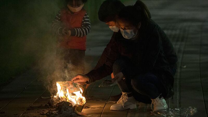 图为，2020年4月4日，湖北省武汉市一家人在街上为其亲人烧纸祭。（美联社）