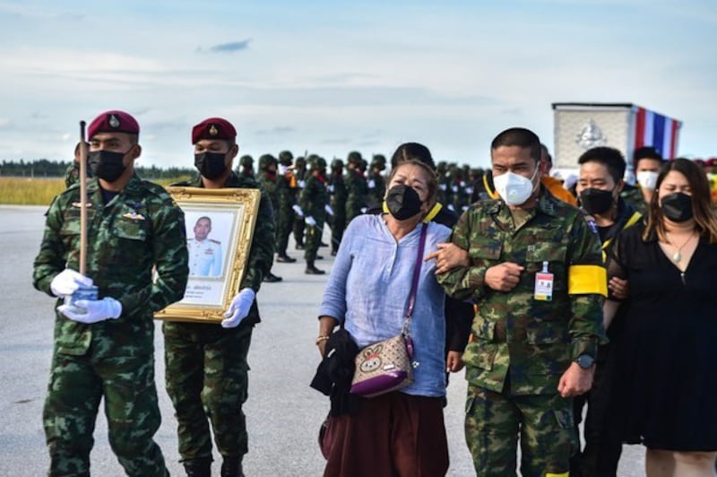 A woman (center) walks with Thai soldiers and family members during the funeral ceremony for her son, a soldier killed during fighting with suspected separatists, at Narathiwat airport in southern Thailand, Oct. 3, 2021. Credit: AFP