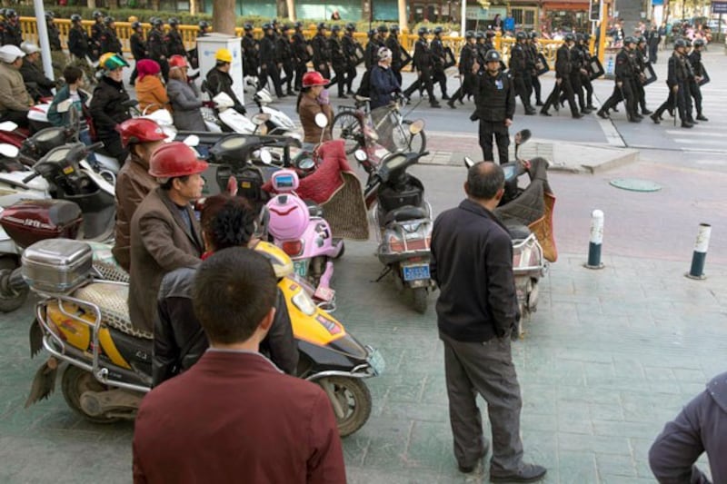 Residents watch a convoy of security personnel in a show of force in central Kashgar in northwestern China's Xinjiang region, Nov. 5, 2017. (Ng Han Guan/AP)