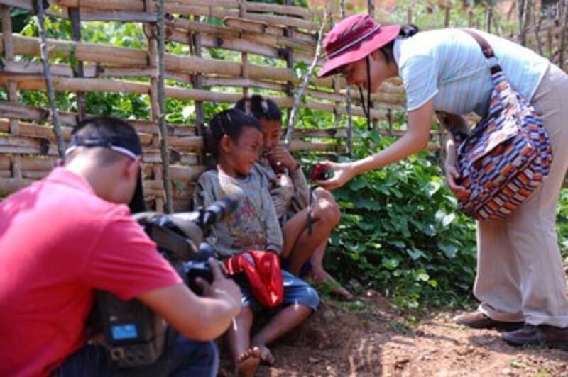 Một nhà báo Nhật Bản (P) chụp hình hai bé trai Hmong hôm 27/5/2011. AFP photo