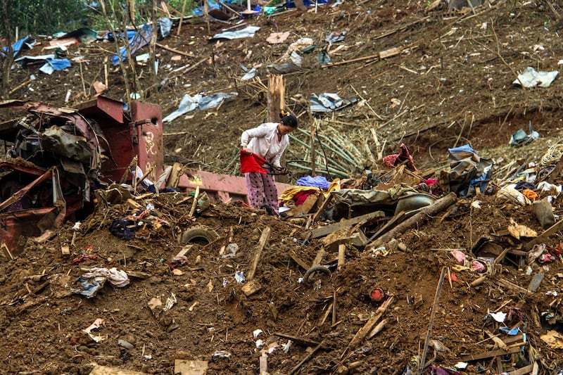 A woman looks through debris in the aftermath of a junta strike on a camp for displaced people near Laiza, northern Myanmar on Oct. 11, 2023. Junta has escalated long range artillery and aerial bombing, both of which have resulted in the increased civilian casualties. (AFP photo)