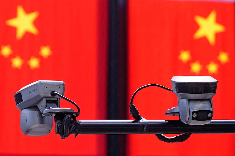 Surveillance cameras in front of Chinese flags at a shopping area in Shanghai, China May 5, 2021.