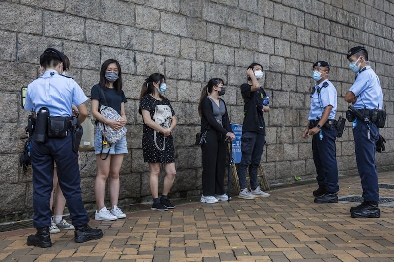 Police perform a stop and search on a group of people outside the High Court in Hong Kong, July 30, 2021. Credit: AFP