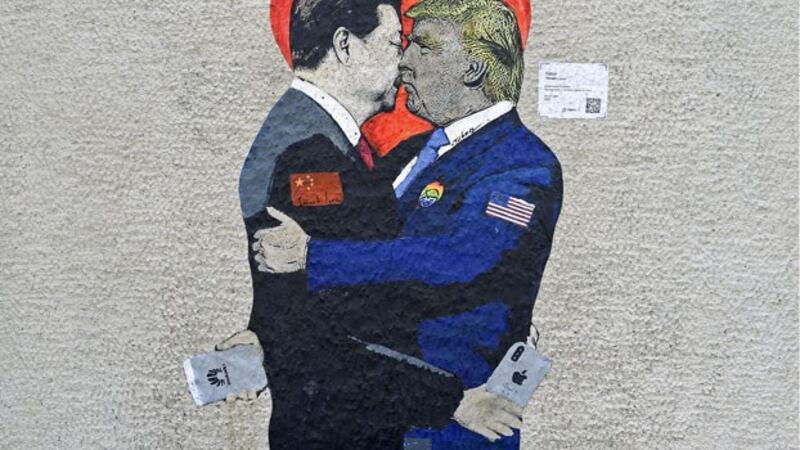 A mural depicting China's President Xi Jinping (L) holding an Apple iPhone kissing US President Donald Trump (R) holding a Huawei smartphone is displayed on a wall in Milan, Italy, June 29, 2019.