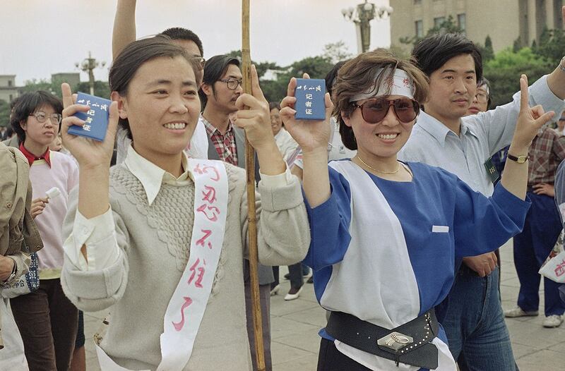 1989年5月16日，中央电视台员工在北京天安门广场加入学生民主罢工，并亮出记者证。（美联社）