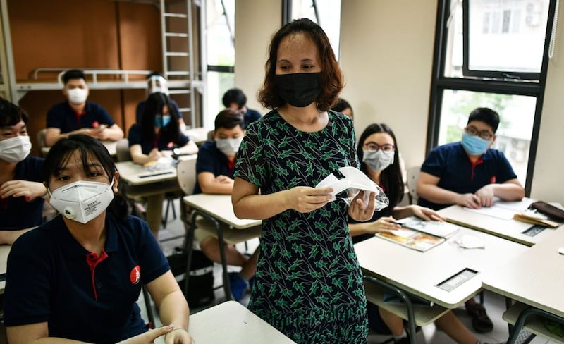 Một giáo viên phát khẩu trang cho học sinh trong lớp học tại trường Marie Curie, Hà Nội vào ngày 4 tháng 5 năm 2020