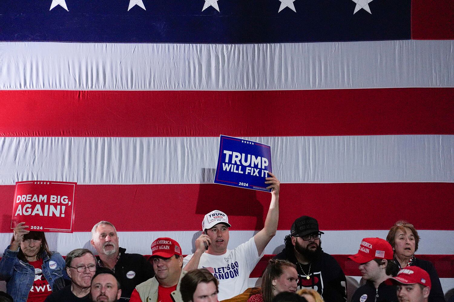 People hold signs ahead of Republican vice presidential nominee Sen. JD Vance speaking during a rally on Nov. 3, 2024, in Derry, New Hampshire.