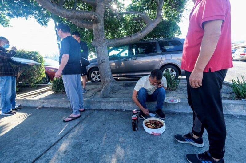 在加利福尼亚州蒙特利公园市，一名男子正在打电话，面前的食物就放在人行道上。图片来源：Ringo Chiu