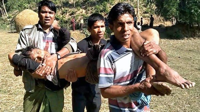 Rohingya men carry a child injured in an explosion on a hill near Htikehtoopauk village, Buthidaung township, in Myanmar's northern Rakhine state, Jan. 7, 2020.