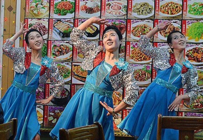 North Korean waitresses perform in front of a large menu at a North Korean restaurant in the border town of Dandong, northeastern China's Liaoning province, Feb. 11, 2013.