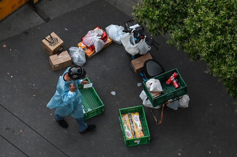 A delivery worker is seen delivering orders to residents next to a checkpoint on a closed street during a Covid-19 coronavirus lockdown in the Jing'an district in Shanghai, May 17, 2022. Credit: AFP