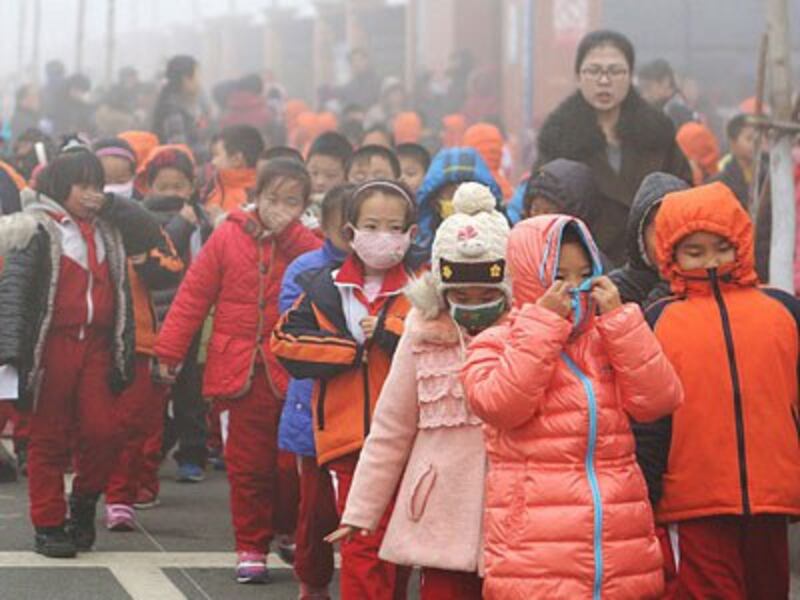 Chinese elementary school students cover their mouths and noses as they leave the schoolyard after classes were suspended because of a 'red alert' for heavy smog in Binzhou, eastern China's Shandong province, Dec. 23, 2015.