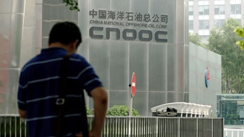 A man stands outside the headquarters building of China National Offshore Oil Corporation (CNOOC) in China's capital Beijing, July 29, 2016.