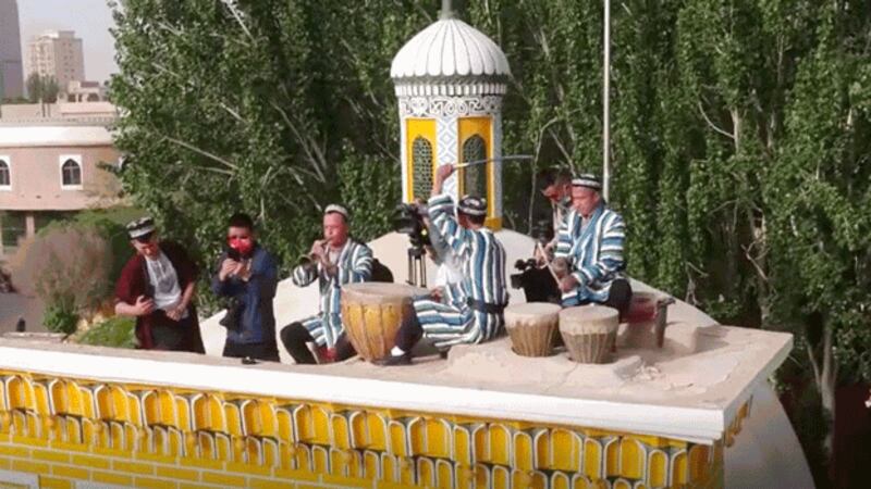 Uyghur musicians play their instruments atop the Id Kah Mosque in Kashgar, northwestern China's Xinjiang region, while other Uyghurs dance in the square below, May 3, 2022. Credit: China News Service video screenshot