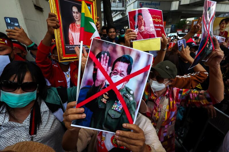 Protesters hold up a picture of Myanmar's junta chief Min Aung Hlaing and pictures of Aung San Suu Kyi during a demonstration outside the Embassy of Myanmar in Bangkok, Thailand, Feb. 1, 2023. Credit: Reuters