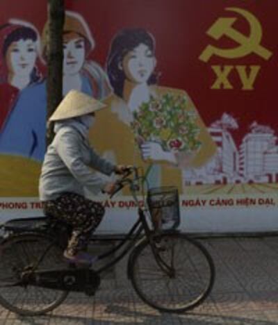 Một người dân đạp xe ngang qua một áp phích tuyên truyền cho ĐCS ở Hà Nội hôm 05/3/2013. AFP photo 