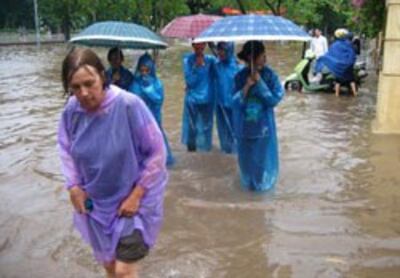 Một khách du lịch nước ngoài lội nước ngập sau trận mưa lớn tại Hà Nội hôm 13/7/2010. AFP photo