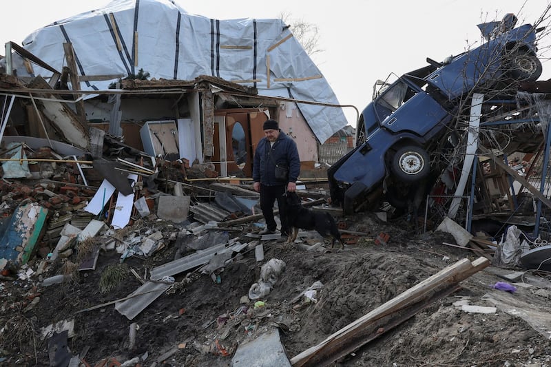 Local resident Volodymyr Alipov, 58, pets a dog amid the remains of his house destroyed last year by a Russian airstrike on the village of Tsyrkuny, Kharkiv region, Ukraine, Monday, March 20, 2023. The United States and its allies are wary of Chinese leader Xi Jinping's 12-point peace plan for Ukraine. Credit: Reuters