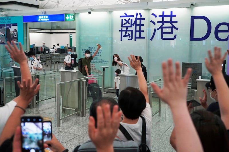 A man bids farewell to relatives and friends at the Hong Kong airport as he and his family prepare to leave the city for England, on May 21, 2021.