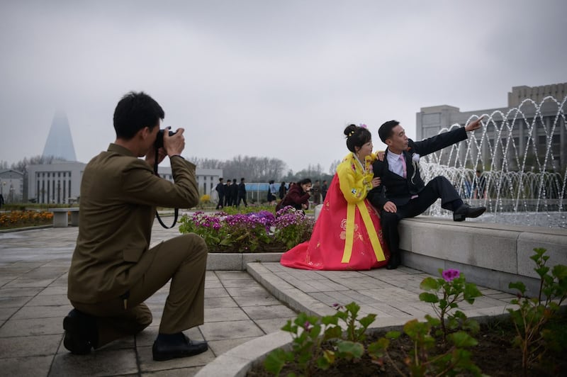 A bride and groom pose before a fountain during a wedding photo shoot at a park in Pyongyang on April 18, 2019. (Photo by Ed JONES / AFP)