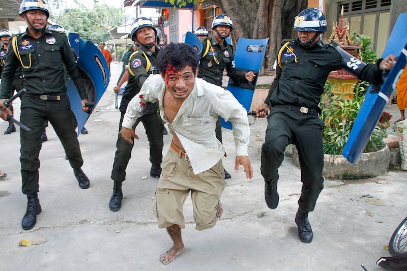 An injured Cambodian worker escapes from riot police in the compound of a Buddhist pagoda in Phnom Penh, Cambodia, Nov. 12, 2013. (AP)