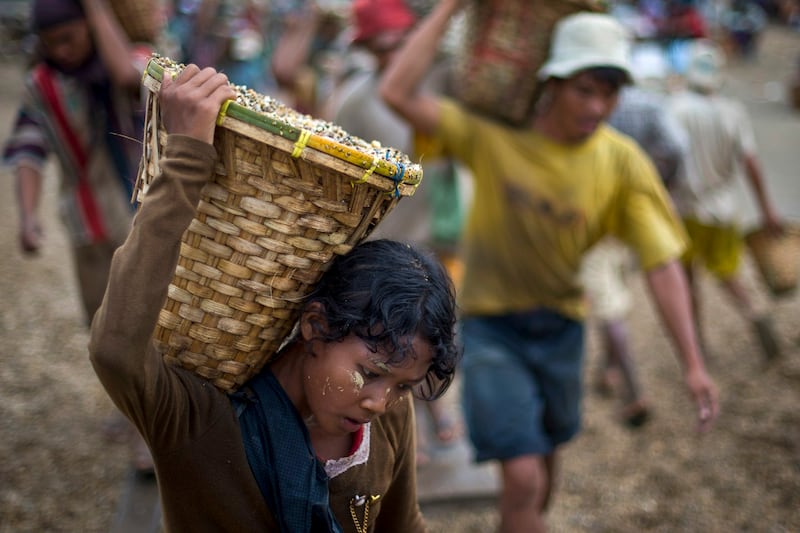 A child carries a basket of stones while unloading a quarry boat with adult workers at a port in Yangon, Myanmar, Sept. 2, 2012. (Alexander F. Yuan/AP)