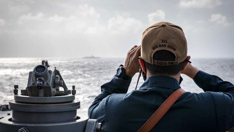 Cmdr. Joseph Gunta, the executive officer of the USS John S. McCain, observes from the vessel as it sails in the South China Sea. Feb. 5, 2021. Credit: U.S. Navy.