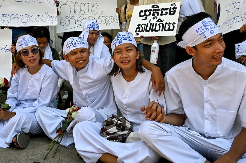 Cambodian environmental activists Ly Chandaravuth, right, Phun Keoraksmey, second from right, Thun Ratha, second from left, Long Kunthea, left, sit outside Phnom Penh municipal court on July 2, 2024. (Tang Chhin Sothy/AFP)