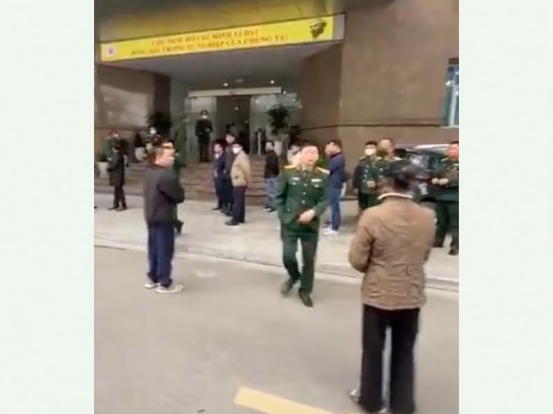 A soldier approaches relatives of Nguyen Van Nghiep outside Hanoi’s Military Hospital 108 to warn them not to film. (Facebook)