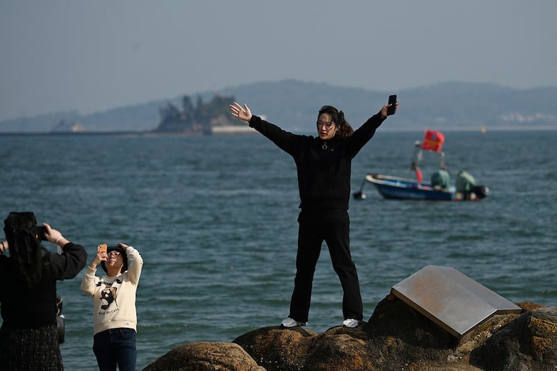 A woman poses on the beach in Xiamen in China's Fujian province on Jan. 10, 2024. (Greg Baker/AFP)