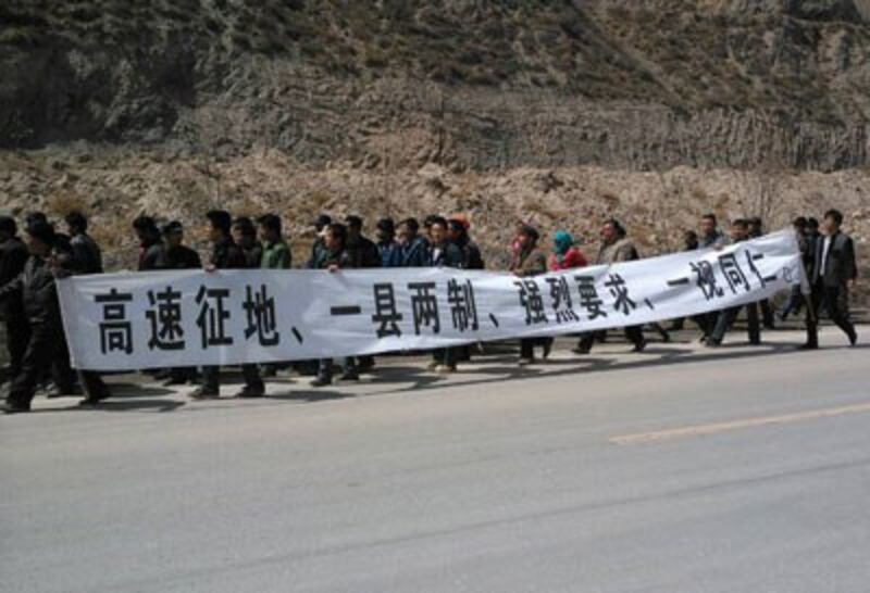 Tibetans carry banners protesting the seizing of their land as they march in Gansu province, April 2, 2014. Credit: RFA listener