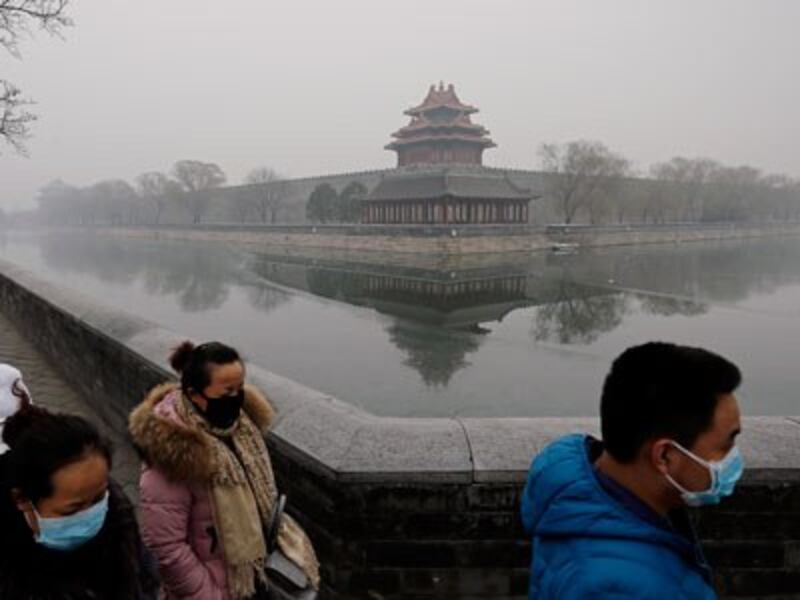 Chinese people wearing masks for protection against pollution walk past the turret of the Forbidden City on a heavily polluted day in Beijing, Dec. 8, 2015. 