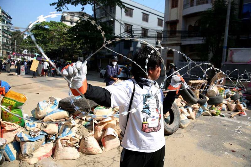 By March, confrontations with security forces had become much more dangerous. Here, a protester adds barbed wire to a barricade in Sanchang, Yangon. (AFP)