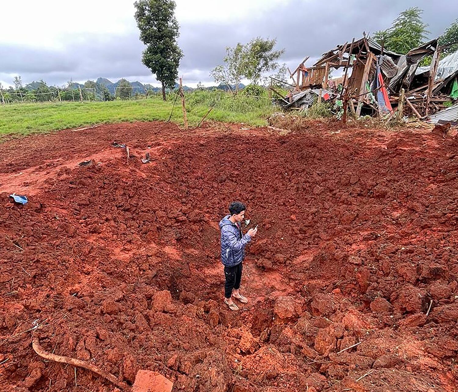 A man stands in a bomb crater at a camp for internally displaced people after junta airstrikes near Pekon township in Myanmar's south Shan state on Sept.  6, 2024.