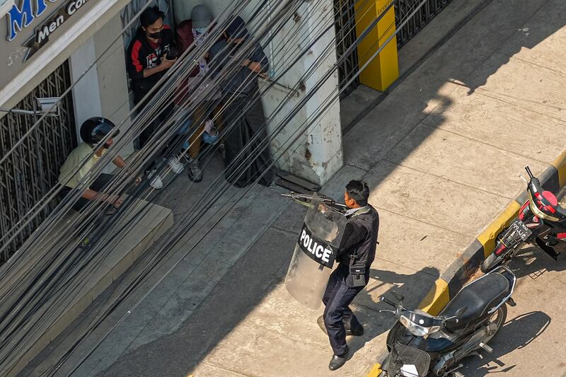 A policeman points his weapon at people amid a crackdown on anti-junta protesters in Shan state's Taunggyi city, Feb. 28, 2021. Credit: AFP