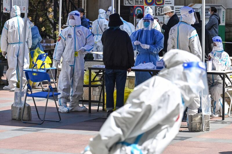 Workers and volunteers look on in a compound where residents are tested for COVID-19 during the second stage of a pandemic lockdown in Shanghai's Jing' an district, April 4, 2022. Credit: AFP