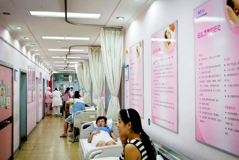 Pregnant women rest inside a corridor displaying posters with information on breastfeeding at Tiantan Hospital's maternity ward in Beijing, Aug. 7, 2013. (Andy Wong/AP)