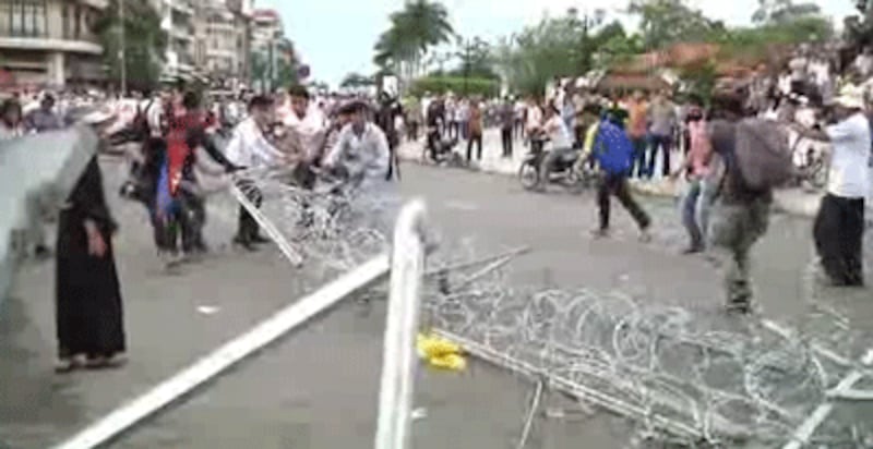 Protesters pulling away a barbed wire barricade near the royal palace, Sept. 15, 2013.(RFA Photo) 