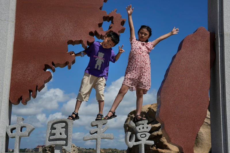 Children pose for photos at the 68-nautical-mile scenic spot, the closest point in mainland China to the island of Taiwan, in Pingtan in southeastern China's Fujian Province, Aug. 5, 2022. Credit: AP