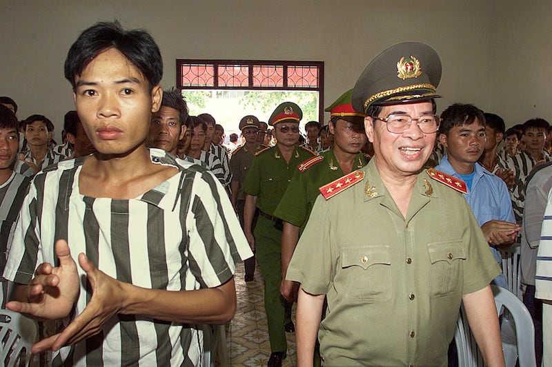 Prisoners stand clapping as Minister of Public Security Le Minh Huong, right, and police officers arrive to attend a ceremony announcing presidential amnesty at Thanh Xuan prison in Northern province of Ha Tay, Sept. 1, 2000. (Hoang Dinh/AFP)