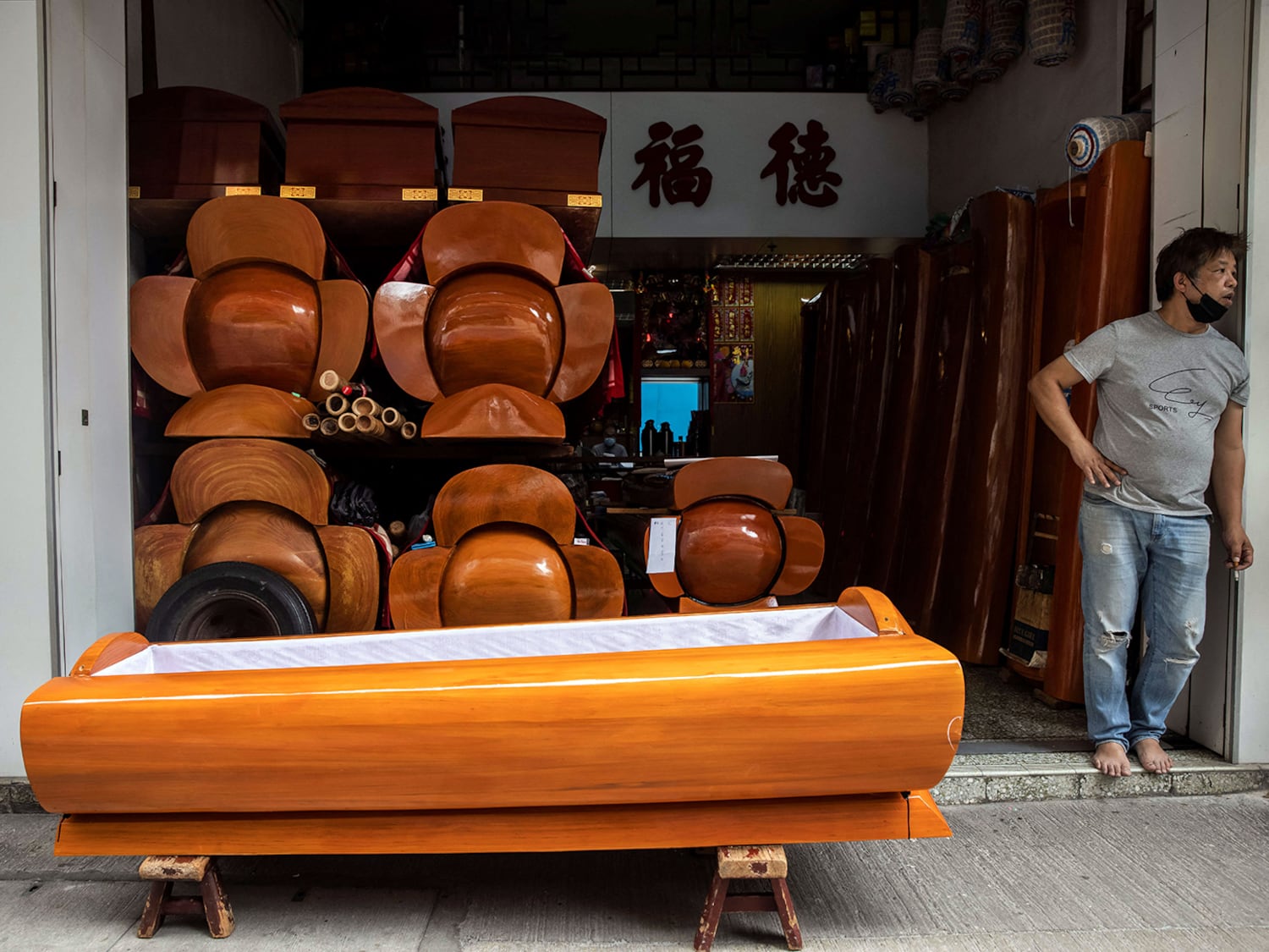 A man stands next to coffins displayed at a funeral services shop in the Kowloon district of Hong Kong, March 17, 2022.