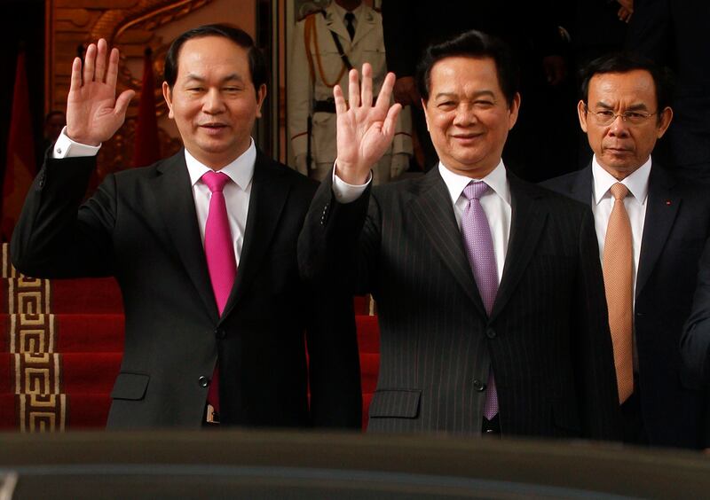 Vietnam's Prime Minister Nguyen Tan Dung, center, and Public Security Minister Tran Dai Quang, left, wave next to Chief Administrator of the Government Office Nguyen Van Nen, right, after a meeting at the Government Office in Hanoi, Dec. 26, 2013. (Kham/Reuters)