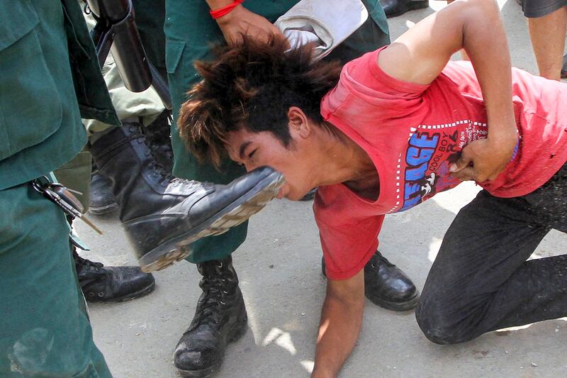 A Cambodian anti-riot police officer kicks a protester during a clash between police and garment workers in Phnom Penh on Nov. 12, 2013. (AFP)