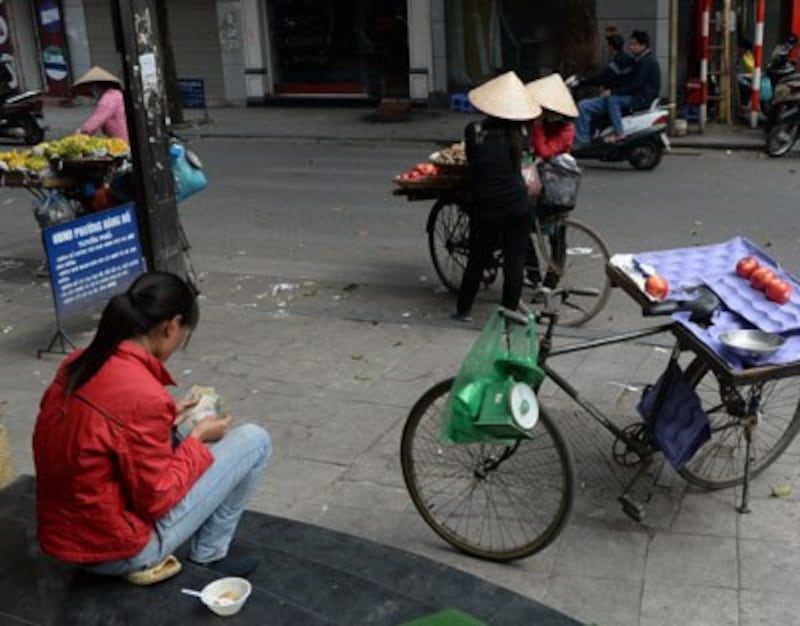 Một người buôn bán vỉa hè đang đếm tiền. Ảnh chụp ngày 27/1/2014 tại Hà Nội. AFP photo