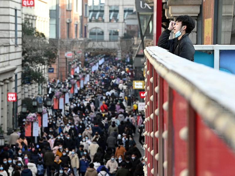 A man looks at people walking along a shopping centre in Wuhan, in China’s central Hubei province on Jan. 1, 2021.