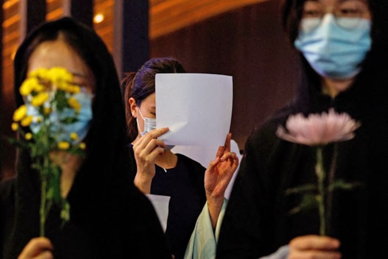 A woman holds a white sheet of paper during a protest over COVID-19 restrictions in mainland China, during a commemoration of the victims of a fire in Urumqi, in Hong Kong, Nov. 28, 2022. (Tyrone Siu/Reuters)